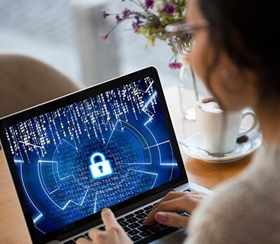 Person working on a laptop with a digital lock screen, representing cloud network security and data protection.