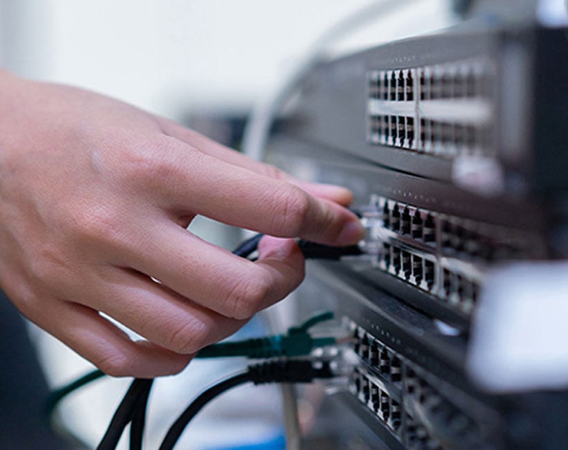 Technician configuring network cables to optimize infrastructure performance.