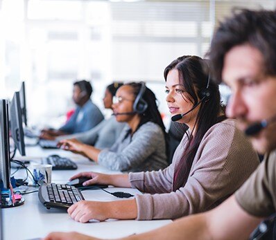 Customer support team providing IT assistance over the phone at a call center.