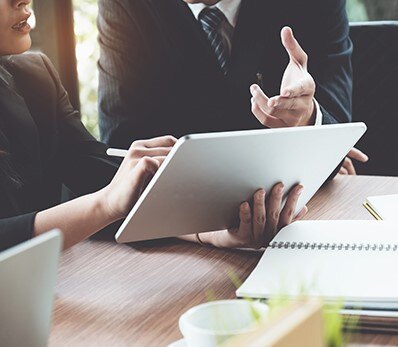 Business professionals discussing IT cost optimization strategies using a digital tablet.