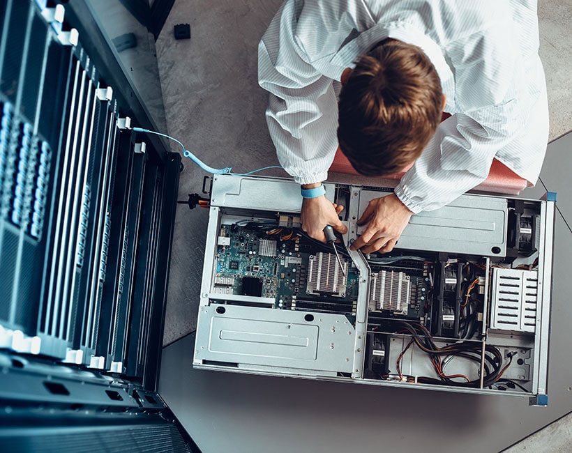 Technician repairing hardware components in an open computer server.