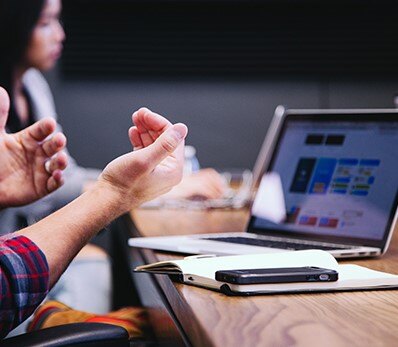 Business professionals discussing IT strategy during a meeting with a laptop and reports.