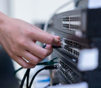 Technician connecting network cables during an IT infrastructure evaluation.