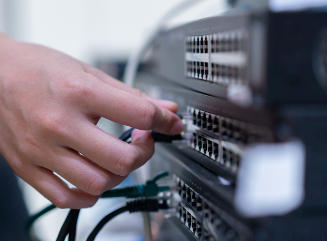 Hand connecting cables to a network switch for data communication.