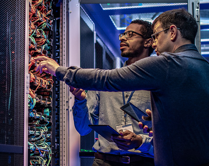 Two network engineers analyzing server connections in a data center.